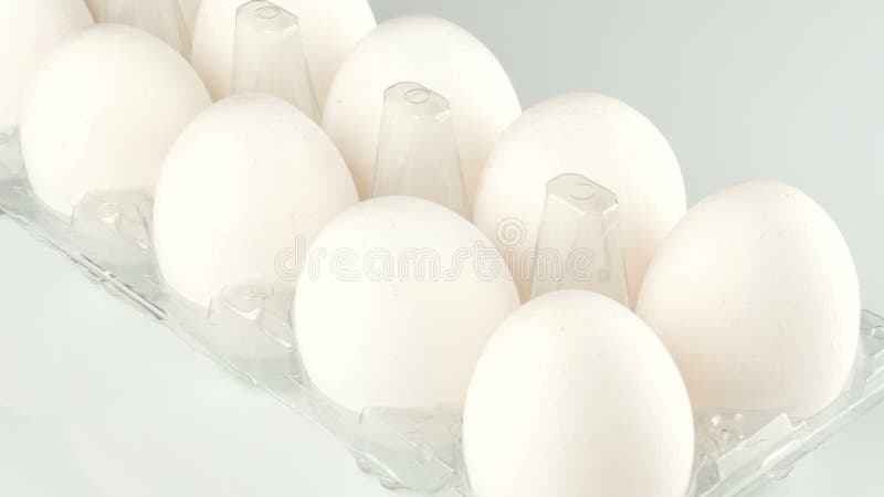 Μεγάλα άσπρα αυγά κοτόπουλου σε έναν διαφανή πλαστικό δίσκο σε ένα άσπρο υπόβαθρο
